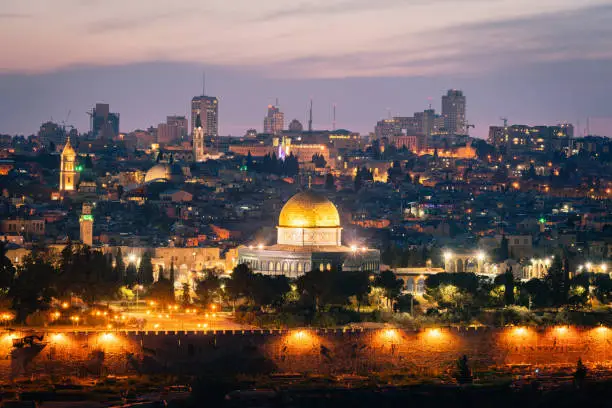 Jerusalem Old Town Cityscape of Temple Mount at Sunset Twilight. Holy land view towards the iconic Al-Aqsa Mosque - Golden Dome of the Rock- and Bell Tower of the Church of the Redeemer,  Church of the Holy Sepulchre and Old Town City Wall. Jerusalem Old Town, Israel, Middle East.