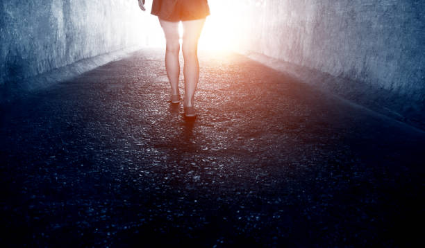 istock Woman walking through a dark tunnel 1219698058