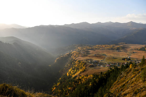 a village on a mountainside is lit by the rising sun in the tusheti region. - tusheti imagens e fotografias de stock