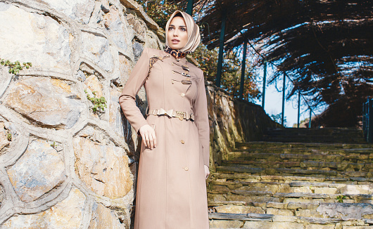 Modern young muslim woman looking away front of the wall