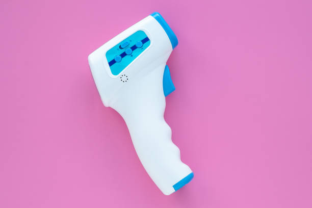 pistola termometro elettronico a fronte infrarossi medica digitale senza contatto per misurare la temperatura. sfondo rosa. diagnostica coronavirus (covid-19). - infrared thermometer foto e immagini stock