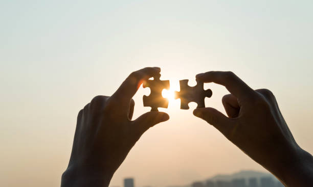 istock Woman hand putting puzzle pieces together in sunset 1219700718