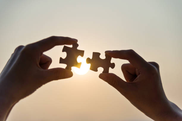 istock Woman hand putting puzzle pieces together in sunset 1219700793