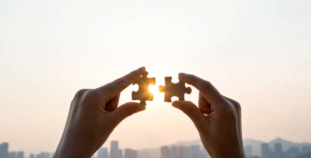 istock Woman hand putting puzzle pieces together in sunset 1219700800