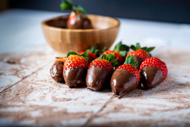 strawberries with chocolate wooden bowl with chocolate, on a white wooden table and surrounded by strawberries smeared with chocolate chocolate covered strawberries stock pictures, royalty-free photos & images