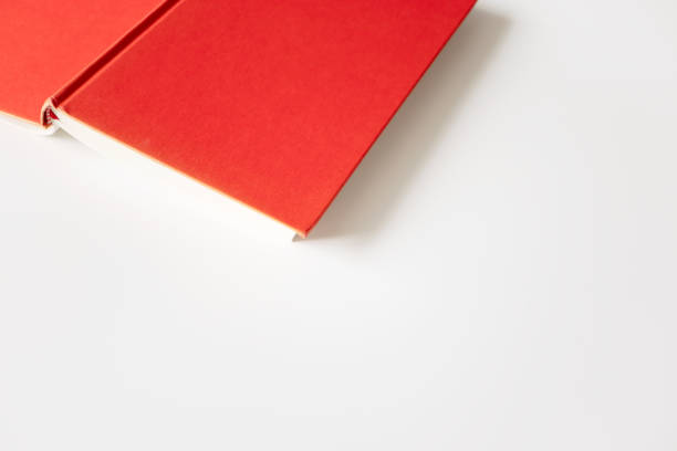 istock Open book in red cover with selective focus and copy space on white background, top view. Concept education, learning and studying, horizontal 1219705185