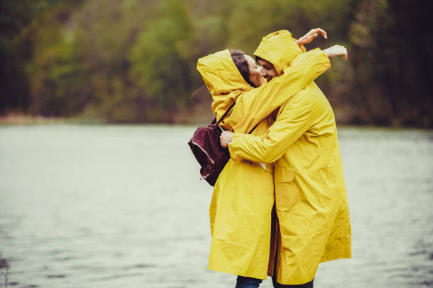 istock Embraced couple in raincoats hiking on a rain 1219705330