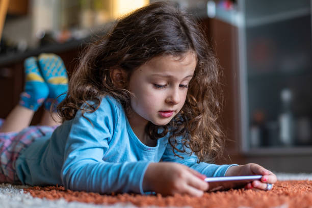 istock Cute little girl lying down looking at mobile 1219706826