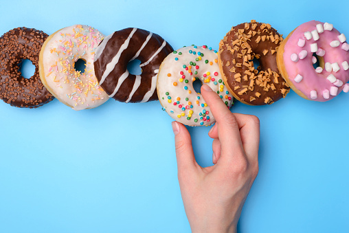 Sweet tooth creative concept. Top above flatlay close up view photo of woman hand taking yummy tasty round donut isolated over blue pastel background