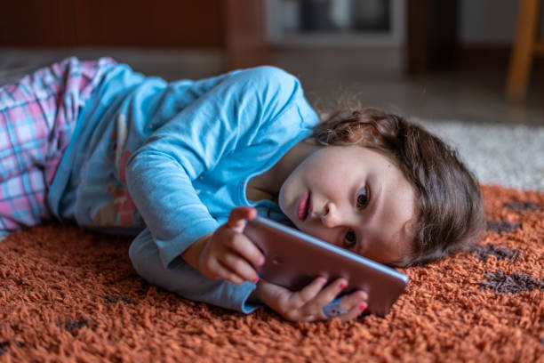 istock Cute little girl lying down looking at mobile 1219710894