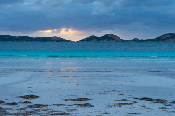 White sand beach at sunset with mountains in the background Photo of a white sand beach and the sea at sunset with mountains in the background cape le grand national park stock pictures, royalty-free photos & images