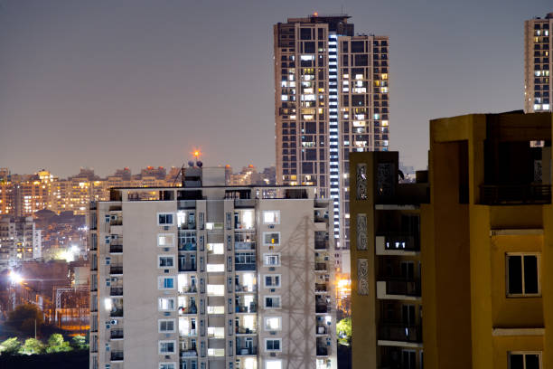 tiro aéreo de edifícios à noite em gurgaon com edifícios menores na frente e arranha-céus ao fundo - bangalore india business building exterior - fotografias e filmes do acervo