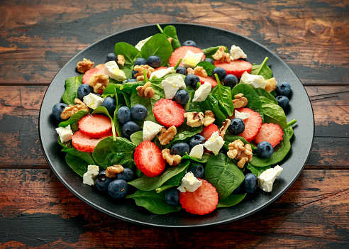 Spinach, Strawberry, blueberry salad with walnut and feta cheese. Summer healthy food.