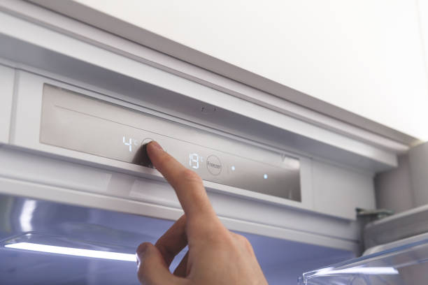 Hand sets temperature of refrigerator stock photo