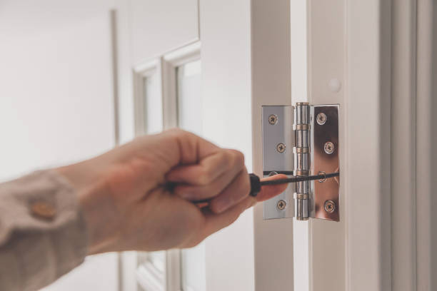 Man remove the door. Twists self-tapping screw with a screwdriver. Stainless door hinges on a white door stock photo