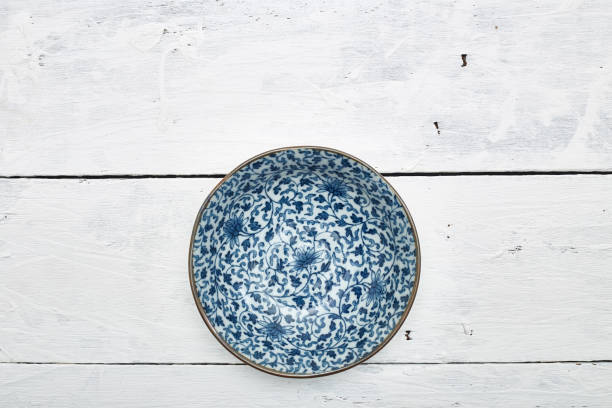 istock Empty ordinary porcelain plate with blue patterns on white wooden table 1219715352