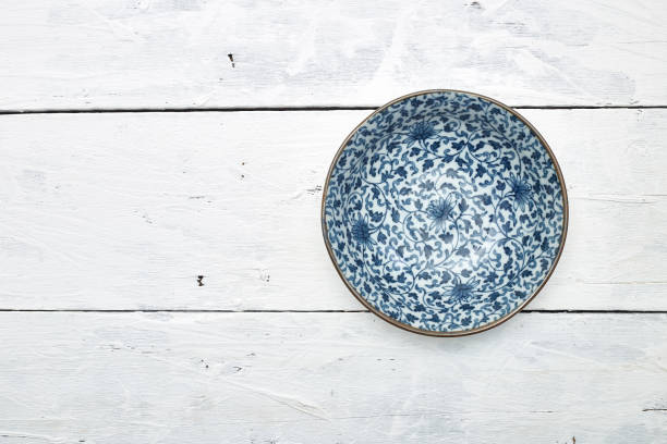 istock Empty ordinary porcelain plate with blue patterns on white wooden table 1219715370