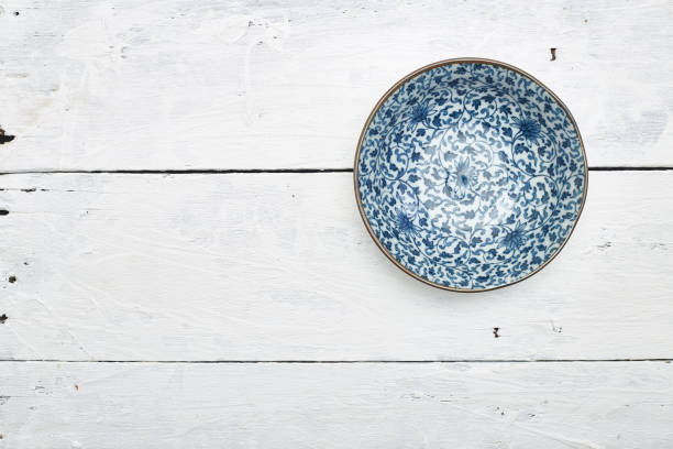 istock Empty ordinary porcelain plate with blue patterns on white wooden table 1219715375