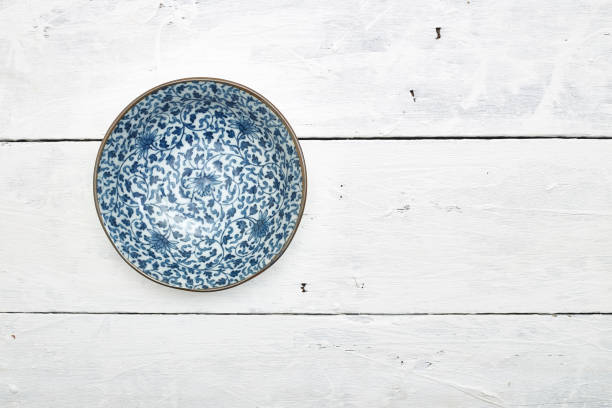 istock Empty ordinary porcelain plate with blue patterns on white wooden table 1219715380