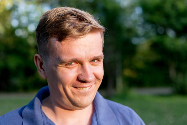 retrato de un joven sobre el fondo de la naturaleza. expresión facial emocional. sonrisa engreída, sentimientos y reacción de la gente. - smug fotografías e imágenes de stock