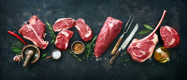 Variety of raw beef meat steaks for grilling with seasoning and utensils Variety of raw beef meat steaks for grilling with seasoning and utensils on dark rustic board chopping food photos stock pictures, royalty-free photos & images