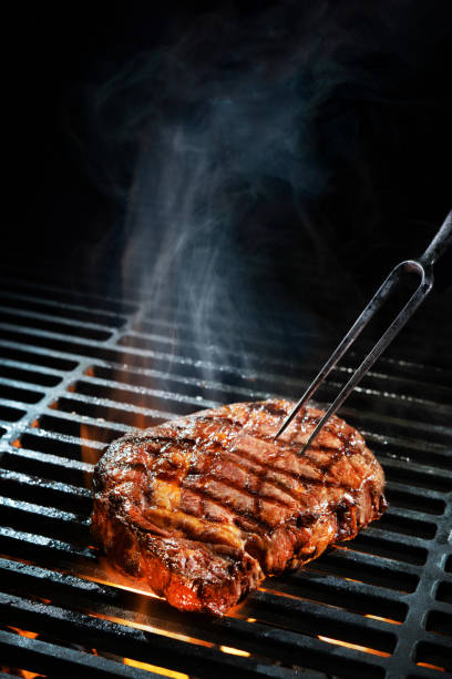 Beef steak on the grill Beef steak on the grill with smoke and flames steak vertical beef meat stock pictures, royalty-free photos & images