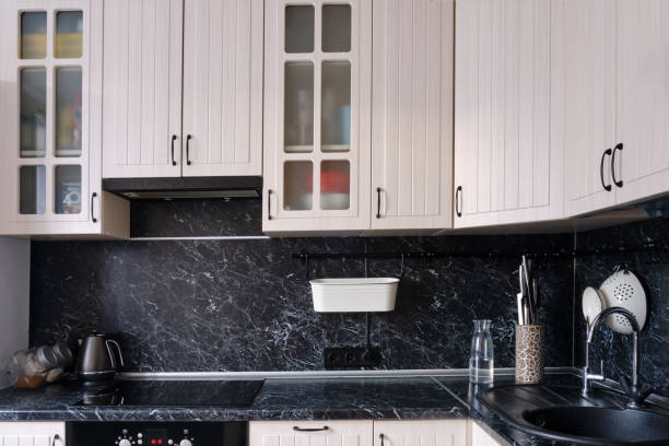istock White wall cabinets in the kitchen with a black countertop. Placed dishes and kitchen utensils on the tables 1219723600