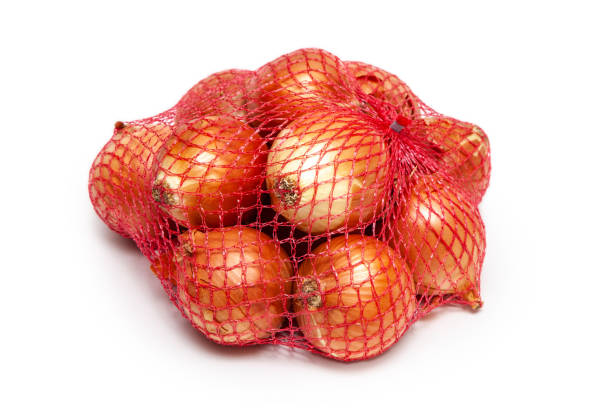 onions in a red packing net isolated on white background - onion bag netting vegetable imagens e fotografias de stock