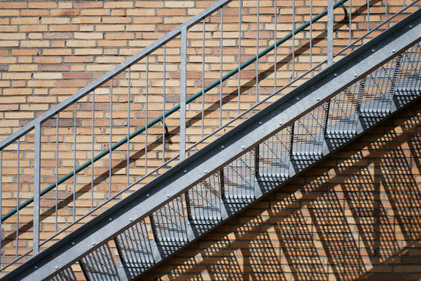 istock Exterior steel staircase on a red brick building wall with harsh shadow casting. 1219723717