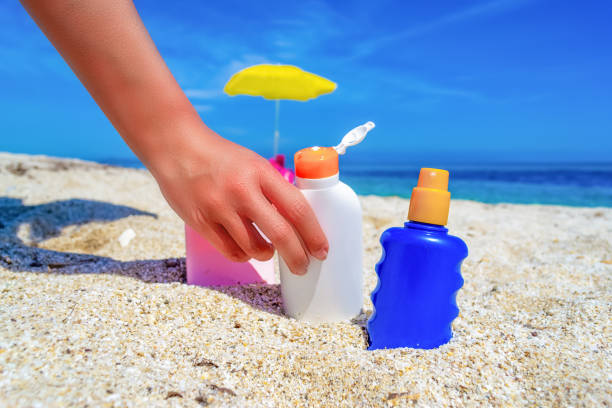 istock Girl holding a suntan bottle on a white sand 1219727551