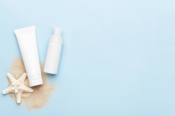 istock Flacon with soft foam and hand cream with blank unbranded mockup. Copy space in right side. Professional facial products and beauty concept on blue summer background. Sea sand and starfish. 1219729190