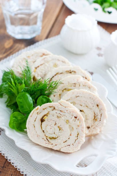 istock Sliced baked chicken breast roll with garlic on a white dish, selective focus 1219729214