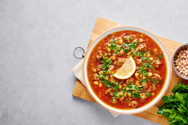 istock Moroccan Harira Soup in white plate on woden board on grey concrete table top. Harira is Moroccan Cuisine dish with lamb or beef meat, chickpeas, lentils, tomatoes, ciliantro. Ramadan Iftar Food. 1219729989