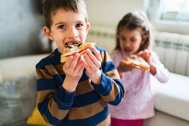istock Beautiful kids eating pizza 1219730141