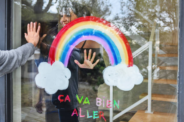 istock Woman painting a rainbow on a window 1219730283