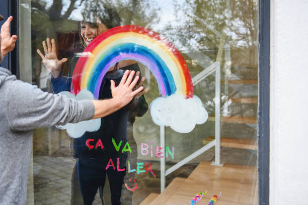 istock Woman painting a rainbow on a window 1219730292