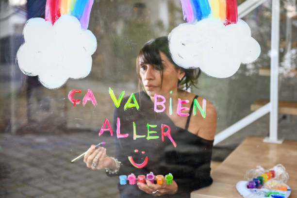 istock Woman painting a rainbow on a window 1219730293