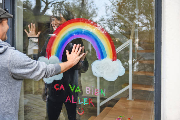 istock Woman painting a rainbow on a window 1219730294