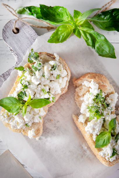 istock 2 sandwiches with soft cheese and Basil on a white wooden background, , Breakfast, top view, copy space 1219731407