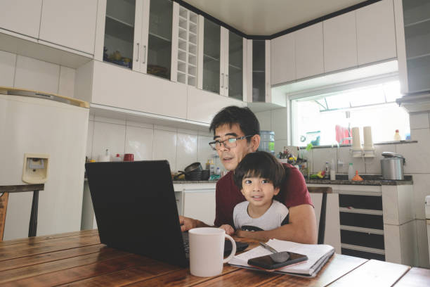 Father working on laptop from home with his cute kid