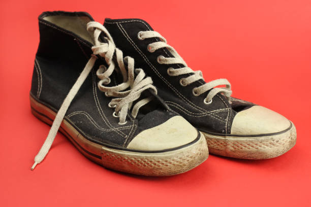 istock sneakers black old, worn, vintage on red background 1219732073