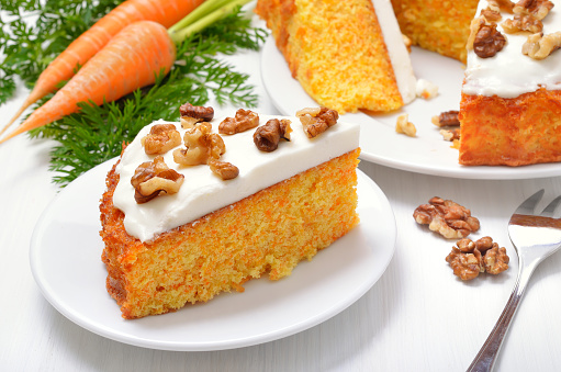 Homemade piece of carrot cake on white plate, close up