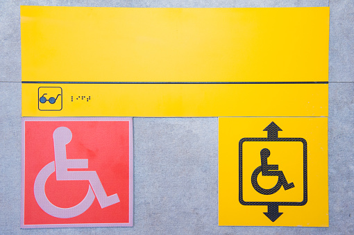 Disabled help call button. Yellow plate with the image of a disabled person and a call button. The complexity of restricting human movement.