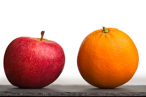 An apple and an orange together on a gray slate surface