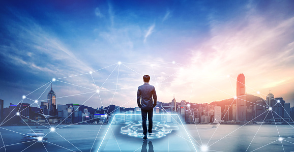 Business technology concept, Professional business man walking on future network city background and futuristic interface graphic at sunset, Cyberpunk color style