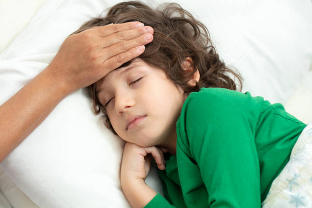 istock Mother checking on sick her son laying in bed 1219735662