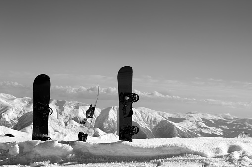 Three snowboards in snowdrift near snowy off-piste slope in sun winter day