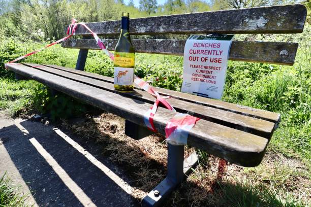 Wimbledon Common, London, 19th April 2020. Signs warning about park benches out of use due to COVID-19. Wimbledon Common, London, 19th April 2020. Signs warning about park benches out of use due to COVID-19., with a wine bottle left abandoned. wimbledon seats stock pictures, royalty-free photos & images