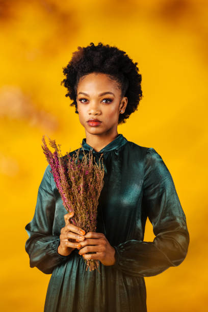 verticale d’une jeune femme élégante dans la robe verte retenant des fleurs de bruyère de bouquet - orange beauty serious retro revival photos et images de collection