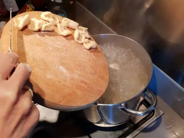 Photo of Putting the pasta to cook in the boiling pot. Italian cuisine of home preparation. Image for recipe instructions.